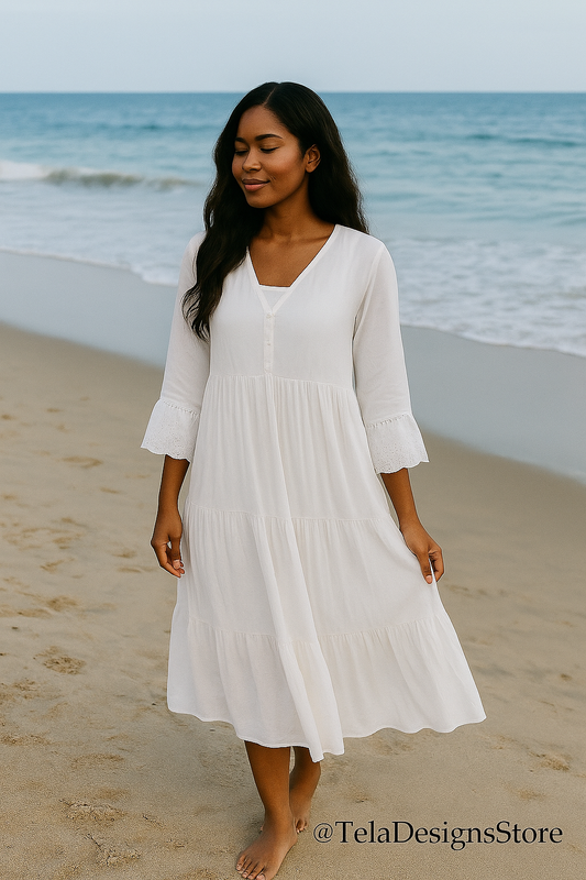 Woman wearing a white cotton boho maxi dress walking barefoot on the beach, eyes closed in peaceful reflection. Ocean waves roll gently behind her. — modest summer fashion from Tela Designs Store.