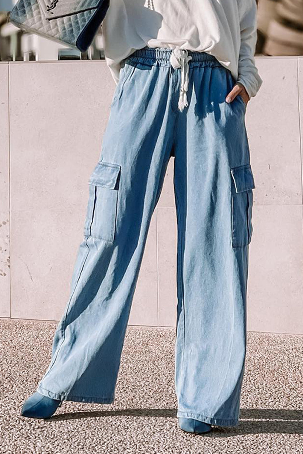 Close-up of light blue modest cargo pants worn with white long-sleeve top in outdoor setting at Tela Designs Store