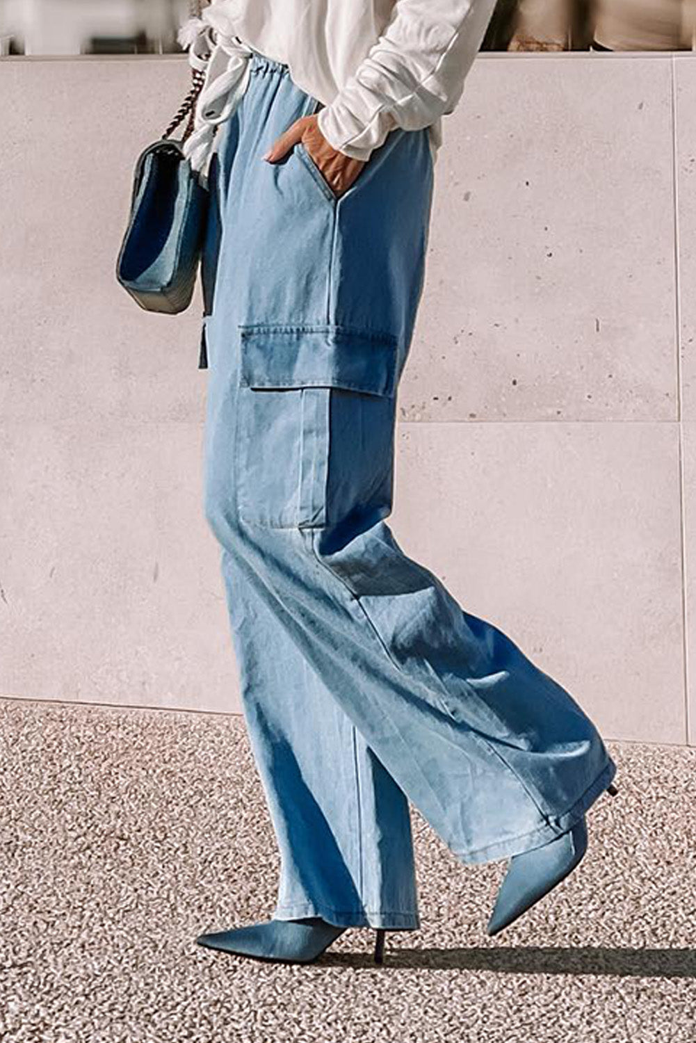Side angle of woman wearing soft cotton chambray wide-leg pants styled with blue heels and a white blouse at Tela Designs Store