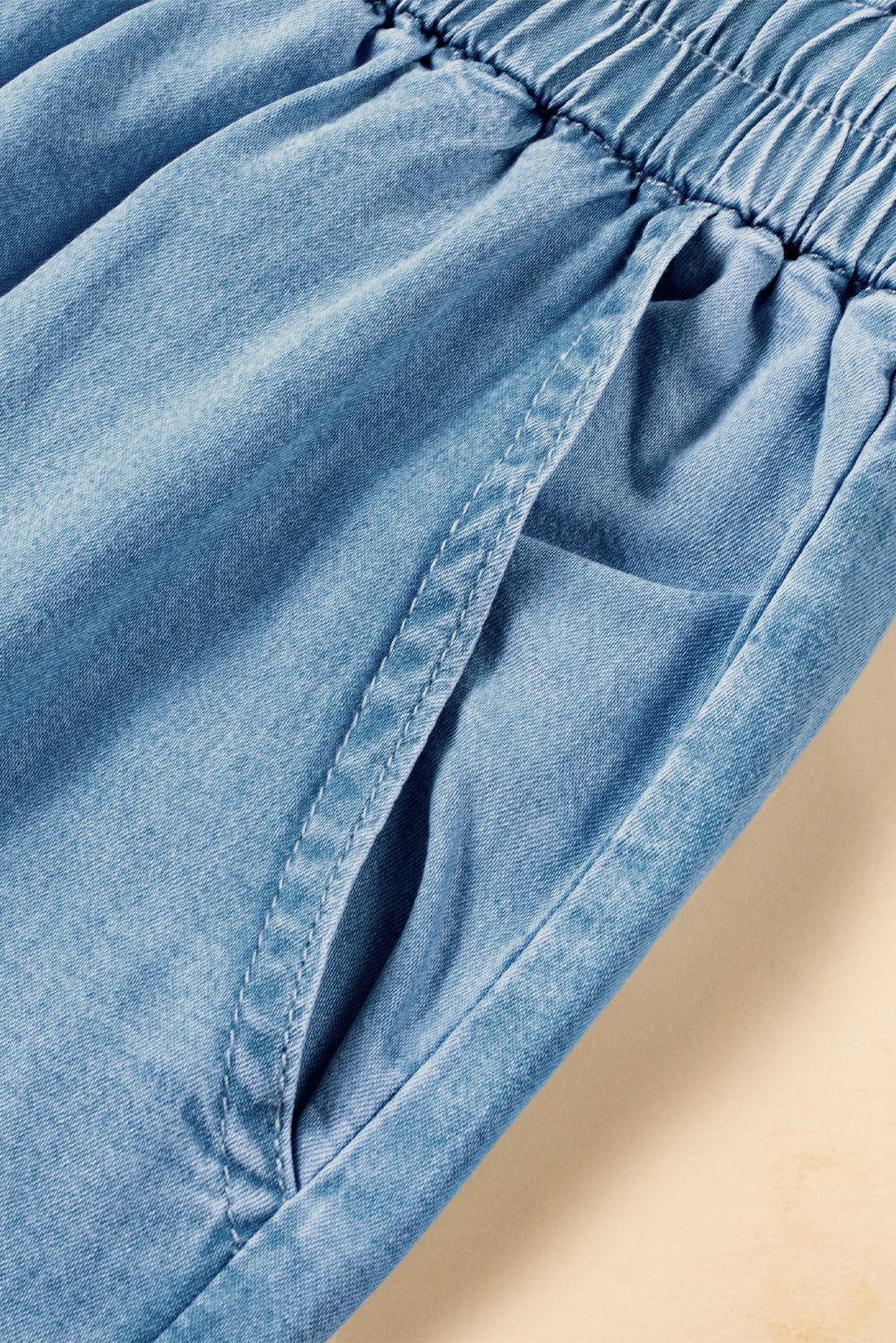 Side pocket detail of light blue chambray pants with elastic waist and visible stitching at Tela Designs Store