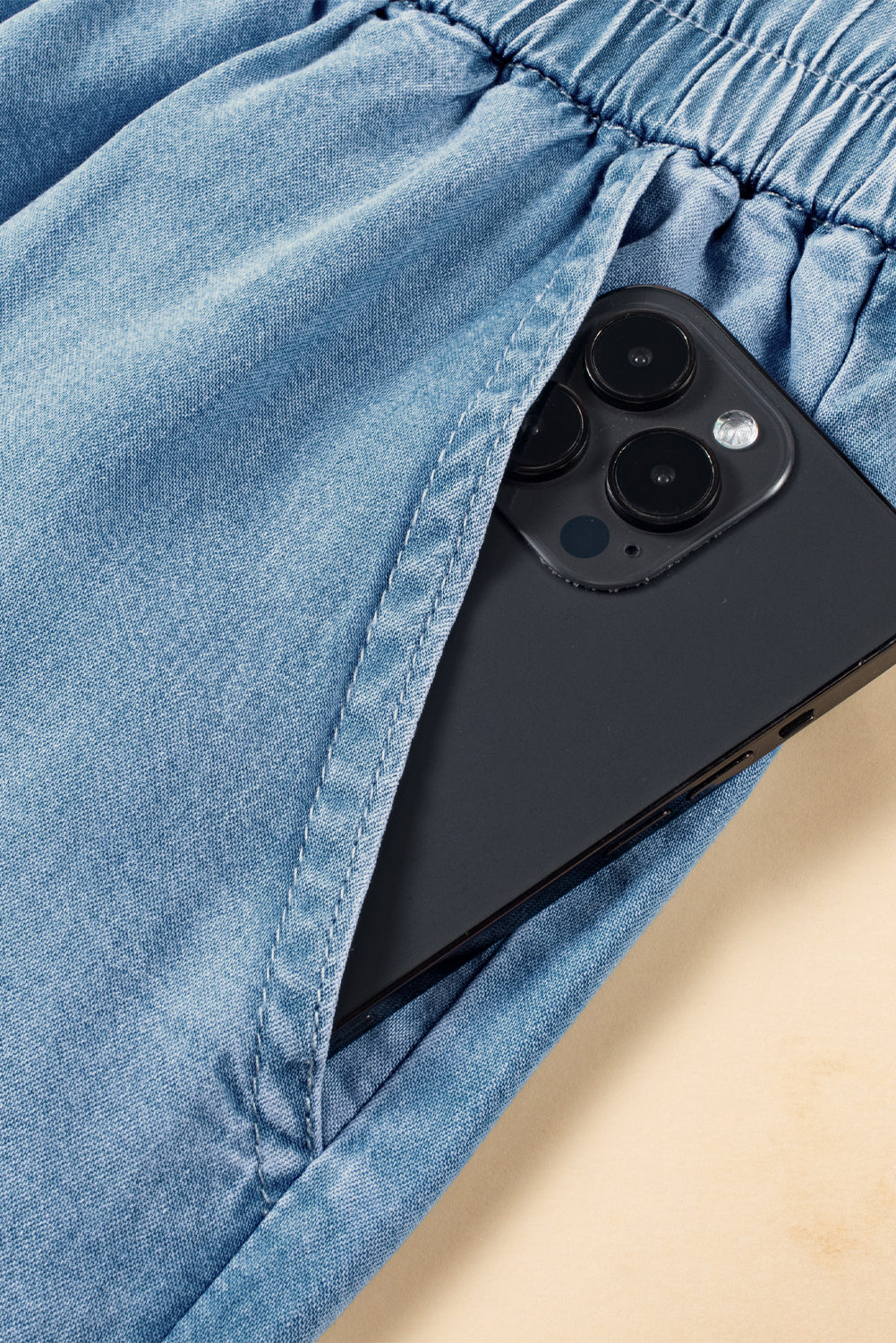 Functional deep pocket of light cotton denim cargo pants holding a black smartphone at Tela Designs Store