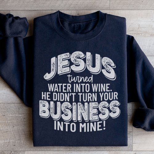 Black/Navy blue sweatshirt close-up showing the bold Christian phrase: "Jesus turned water into wine He didn't turn your business into mine"