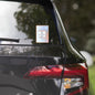 Rise Shine Give God The Glory 5"x5" holographic sticker with neon orange-pink border and red 'Tela Designs Store' branding displayed on the rear window of a black minivan. The sticker features a bold Christian slogan with a radiant holographic design, perfect for adding a faith-based message to vehicles.