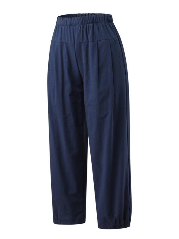 Navy blue cotton linen harem pants angled sideways highlighting the loose drape and cropped ankle-length hem with slanted functional pockets at Tela Designs Store.