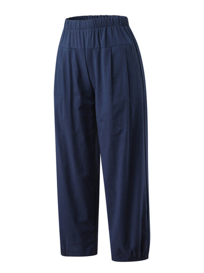 Navy blue cotton linen harem pants angled sideways highlighting the loose drape and cropped ankle-length hem with slanted functional pockets at Tela Designs Store.