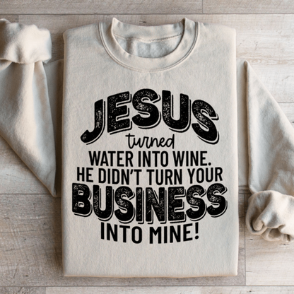 Folded sand-colored Christian fleece sweatshirt with biblical humor text design, "Jesus turned water into wine He didn't turn your business into mine!"